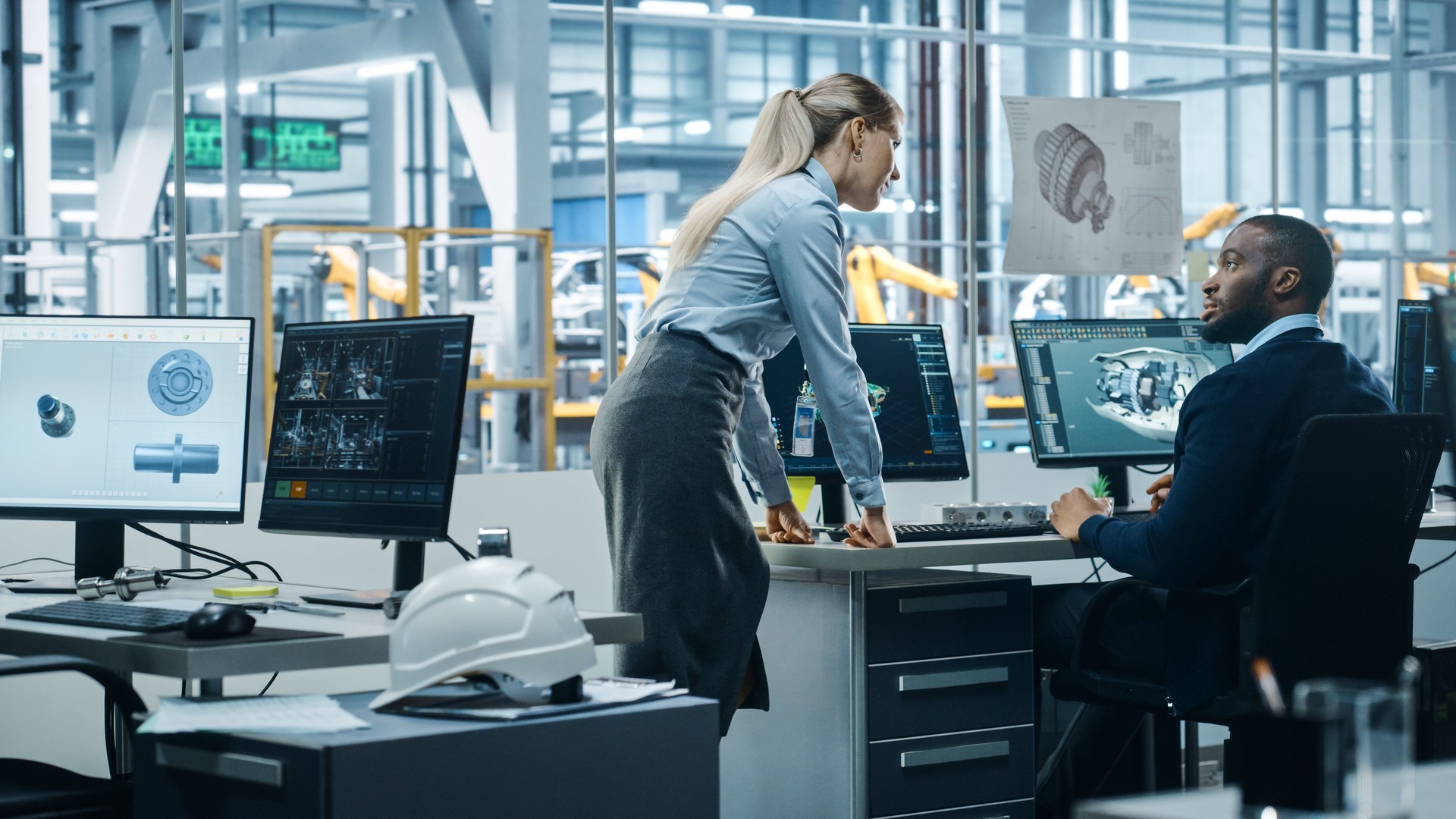 Car Factory Office: Project Manager Talks to Engineer Working on Computer, uses CAD Software with 3D Green Energy Turbine Engine, Electric Car. Automated Robot Arm Assembly Line Manufacturing Vehicles